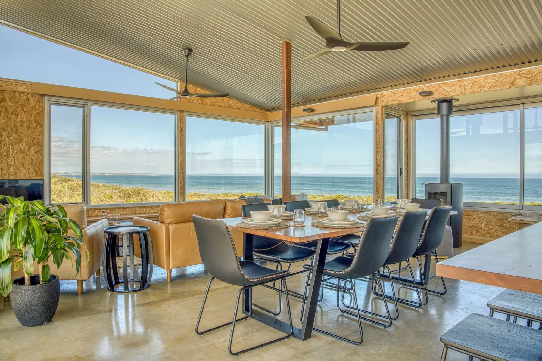 Dining table for eight beneath a raked ceiling with ocean views